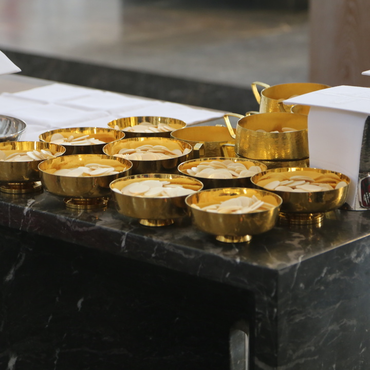 Auf einem Tisch stehen Kelche und Schalen für die Eucharistiefeier.