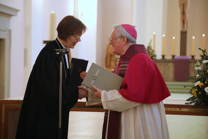 Bischof Friedhelm Hofmann und Regionalbischöfin Gisela Bornowski überreichen sich gegenseitig eine Ausgabe der Einheitsübersetzung beziehungsweise der Lutherbibel.