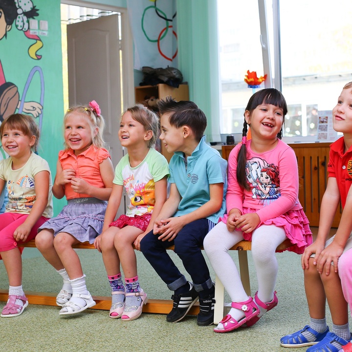 Kindergartenkinder sitzen im Stuhlkreis und lachen. 
