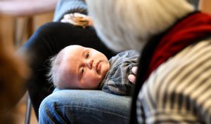 Ein Baby liegt bei einem Vorbereitungskurs zur Taufe am 17. März 2018 in Dietzenbach auf den Beinen des Vaters und blickt in das Gesicht der Referentin.