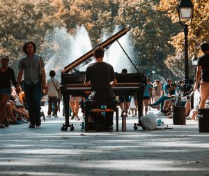 Ein Mann spielt im Washington Square Park in New York vor einer Fontäne Klavier.