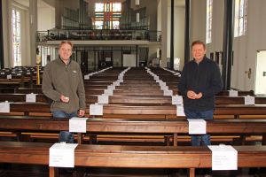 Pastoralreferent Holger Oberle-Wiesli (links) und Pfarrer Dr. Heinrich Skolucki in der Pfarrkirche in Elsenfeld. Das Foto entstand zu Beginn der Aktion. Mittlerweile  liegen noch viel mehr Zettel mit Namen auf den Bänken.