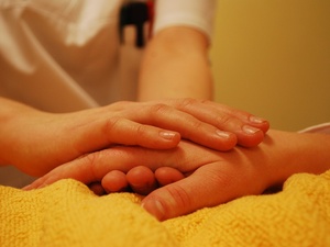 Eine Pflegerin greift die Hand eines Kranken.