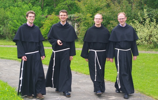 Brüder der Franziskaner-Minoriten laufen einen Weg entlang