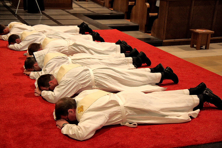 Priesteramtskandidaten liegen vor ihrer Weihe auf dem Boden.