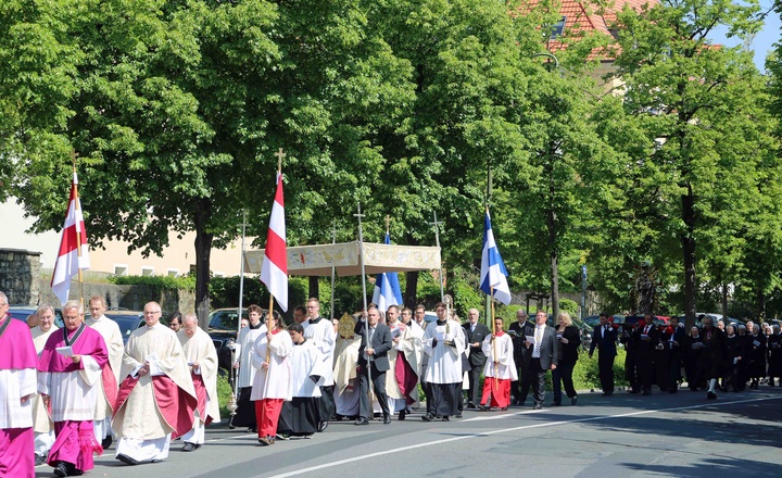 Gläubige ziehen zur Fronleichnamsprozession über eine Straße.