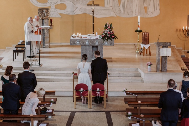 Ein Brautpaar steht in einer Kirche vor den Stufen des Altars.