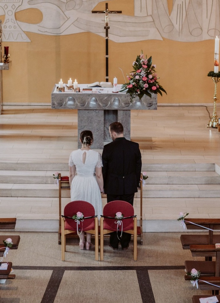 Ein Brautpaar steht in einer Kirche vor den Stufen des Altars.