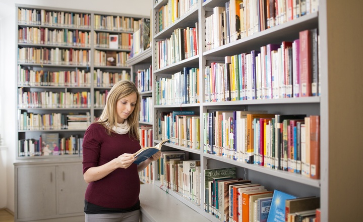 Eine Frau liest in einer Bibliothek ein Buch 