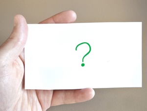 Eine Hand hält eine Karte mit einem Fragezeichen darauf